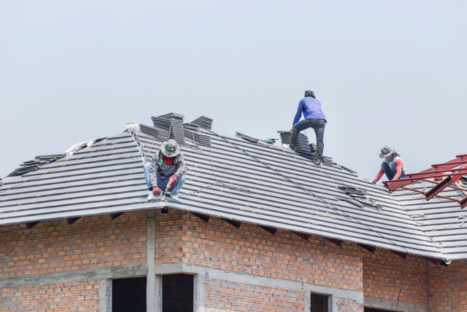 A Group of Construction Workers Are Working on The Roof of A Building — Coffs Coast Plumbing in Korora, NSW