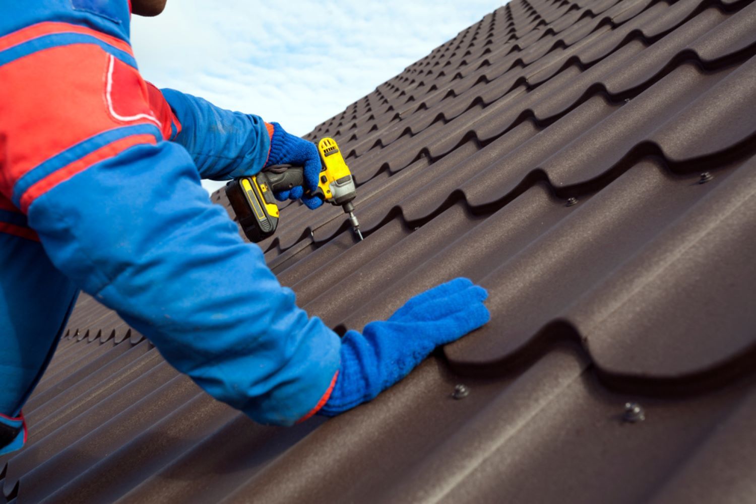 A Man Is Working on A Roof with A Drill — Coffs Coast Plumbing in Korora, NSW