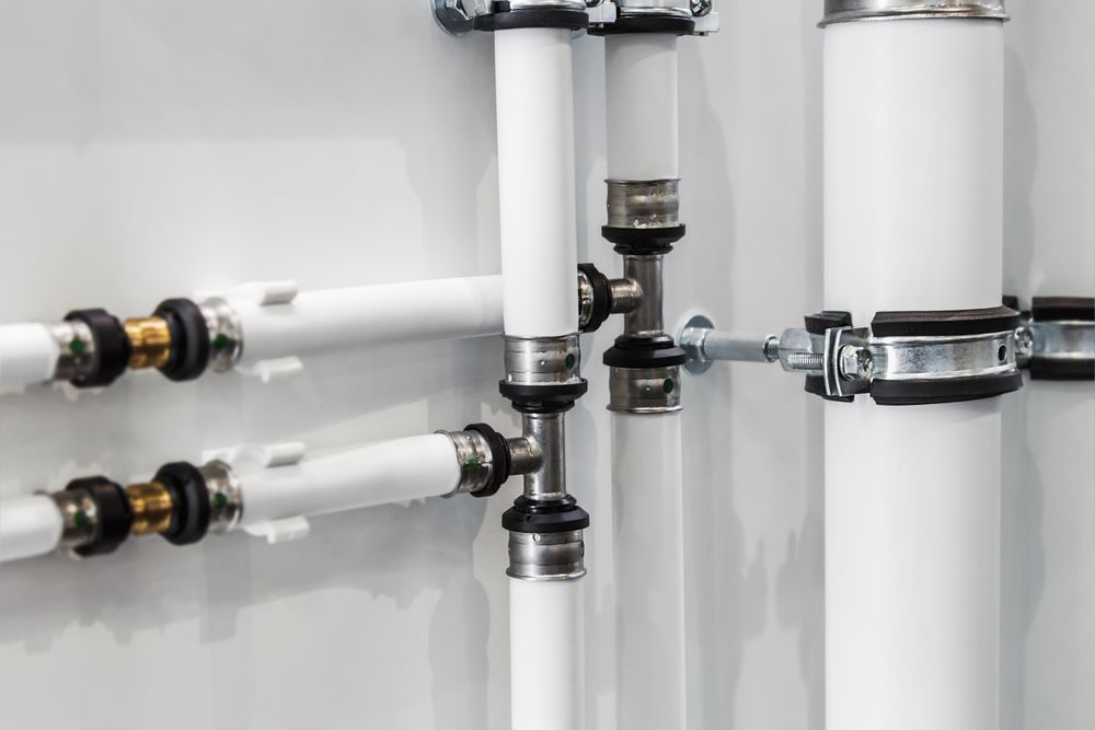 A Close up Of a Row of White Pipes Attached to A Wall — Coffs Coast Plumbing in Urunga, NSW
