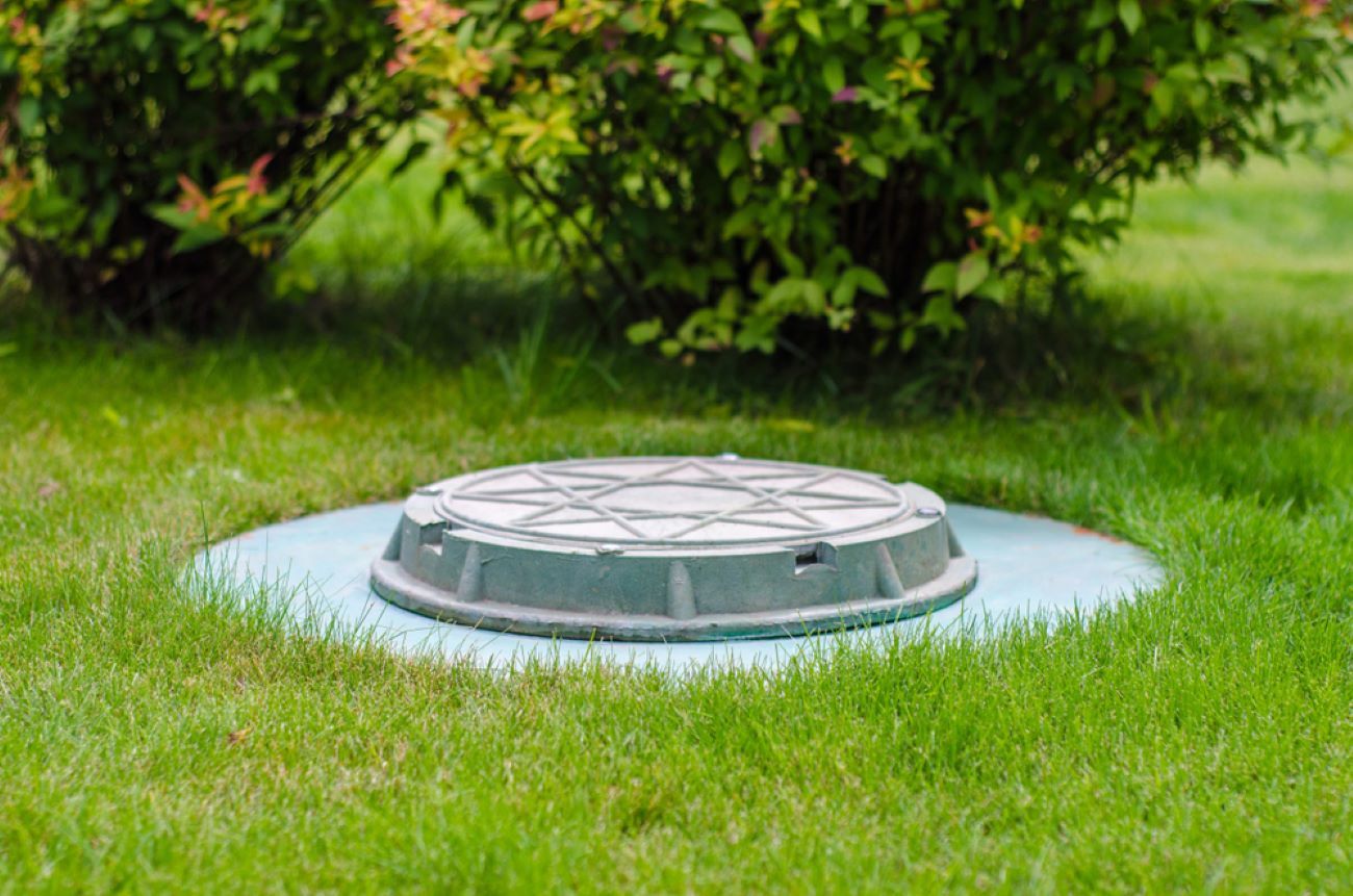 A Manhole Cover Is Sitting in The Middle of A Lush Green Field — Coffs Coast Plumbing in Korora, NSW