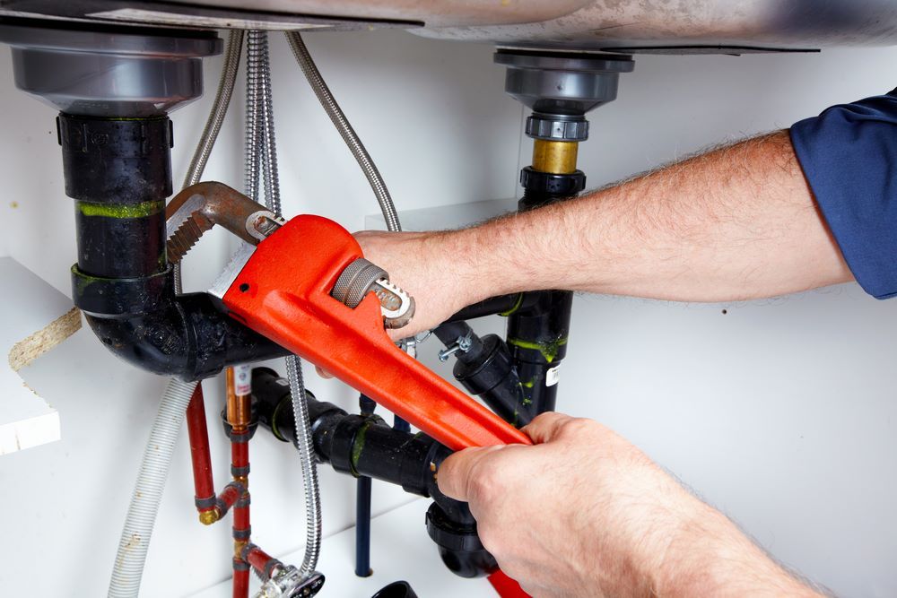 A Plumber Is Fixing a Sink with A Wrench — Coffs Coast Plumbing in Korora, NSW