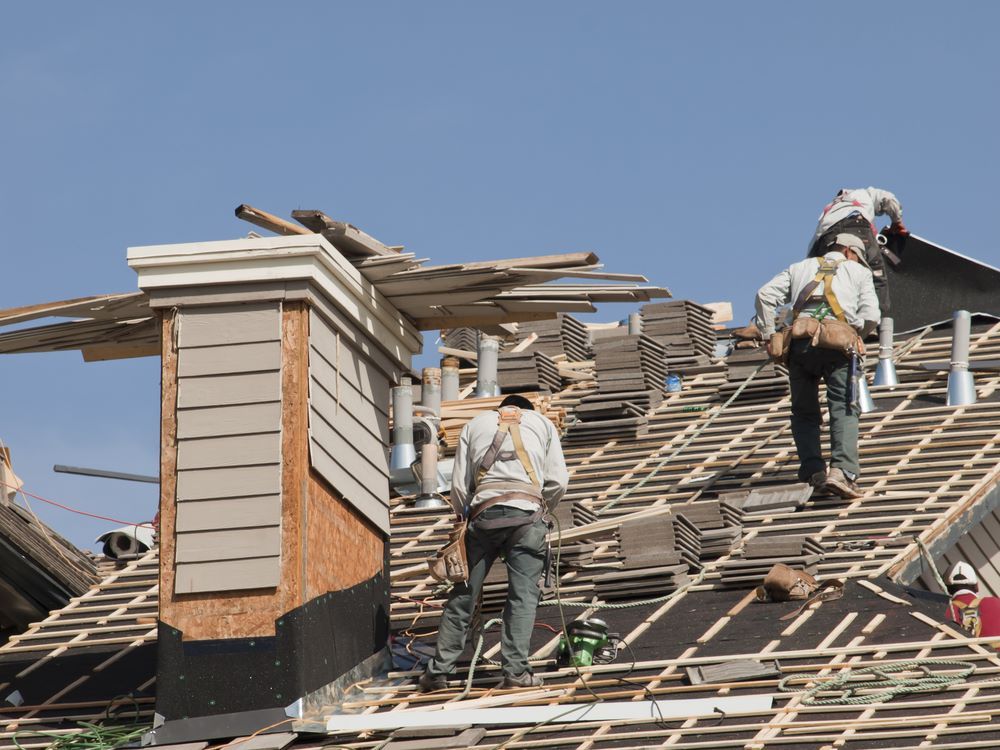 A Group of Men Are Working on The Roof of A House — Coffs Coast Plumbing in Korora, NSW