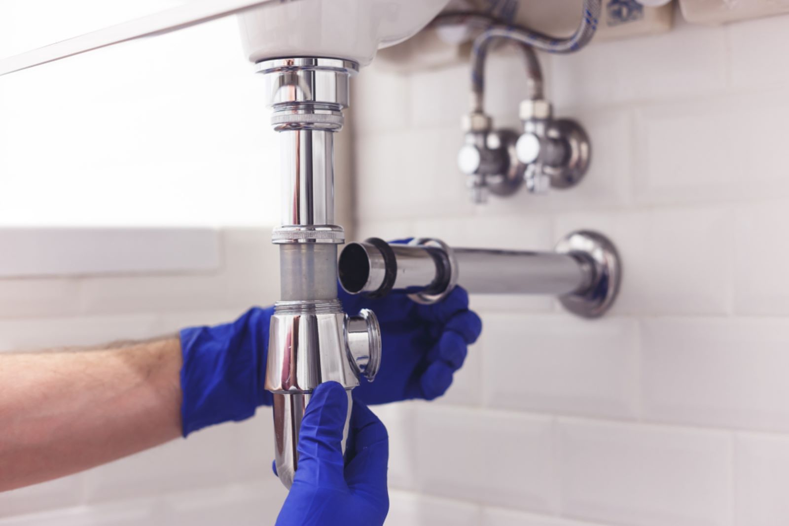 A Plumber Is Fixing a Sink Pipe in A Bathroom — Coffs Coast Plumbing in Korora, NSW