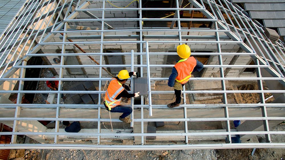 Two Construction Workers Are Working on The Roof of A Building — Coffs Coast Plumbing in Korora, NSW