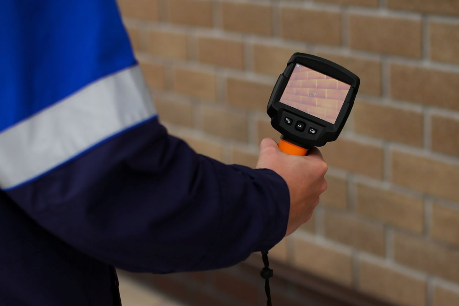 A Person Is Using a Leak Detector in Front of A Brick Wall — Coffs Coast Plumbing in Urunga, NSW