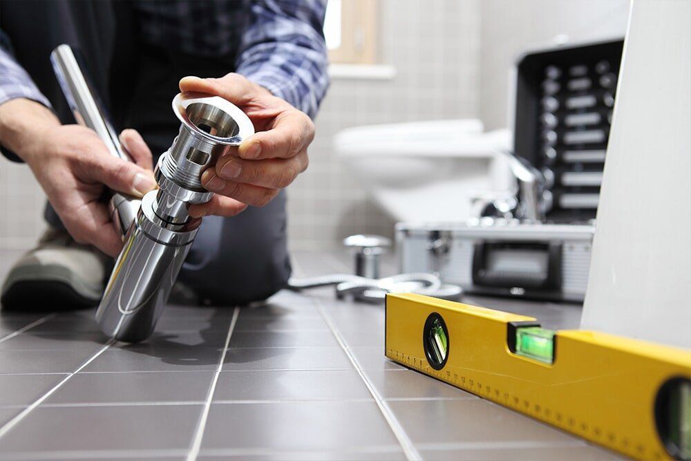 A Plumber is Fixing a Sink in a Bathroom — Coffs Coast Plumbing in Korora, NSW