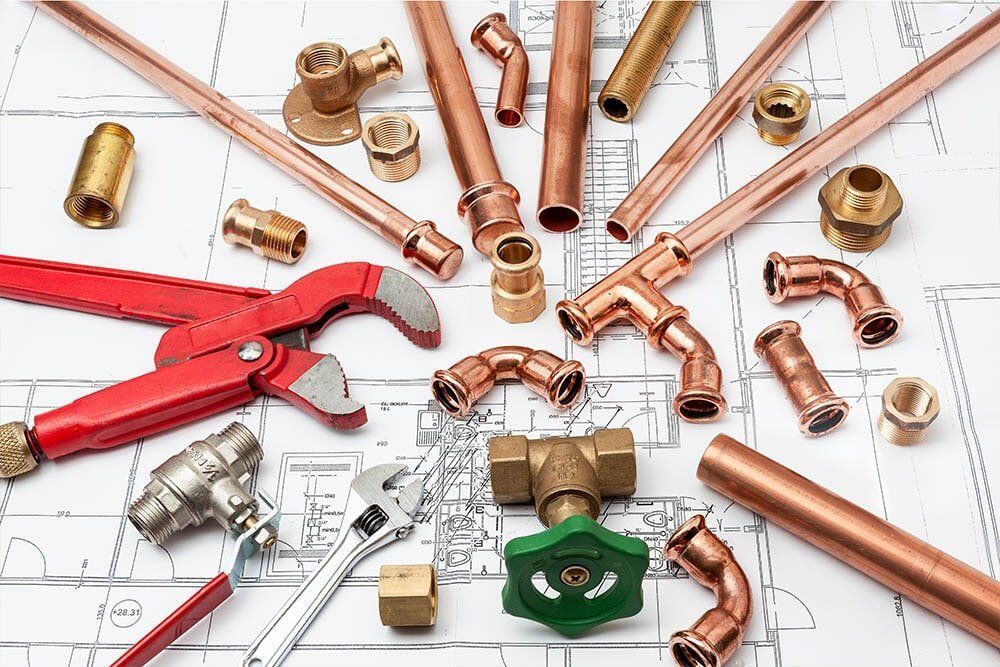 A Bunch of Copper Pipes and Tools Are Laying on Top of a Blueprint — Coffs Coast Plumbing in Korora, NSW