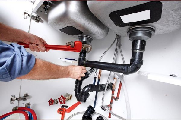 A Plumber is Fixing a Sink With a Wrench — Coffs Coast Plumbing in Korora, NSW