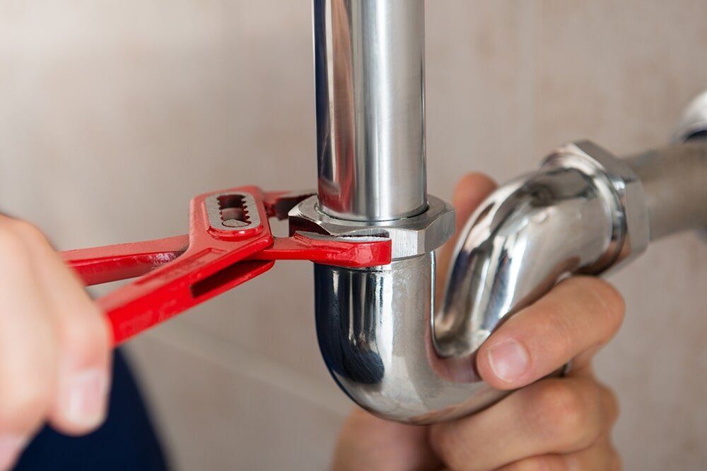 A Plumber is Fixing a Pipe With a Wrench — Coffs Coast Plumbing in Korora, NSW