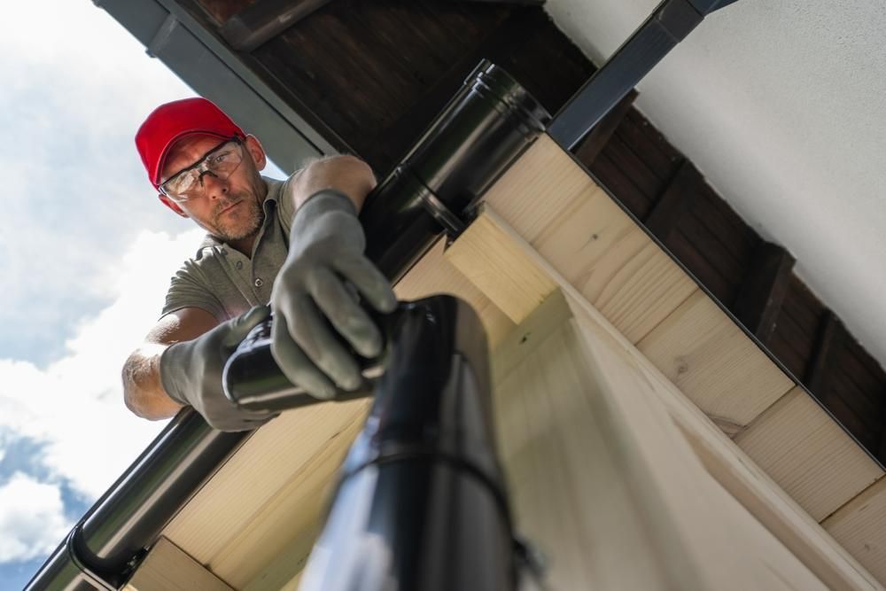 A Man Is Working on A Gutter Pipe — Coffs Coast Plumbing in Korora, NSW