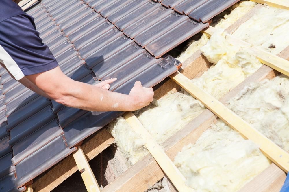 A Man Is Working on The Roof of A House — Coffs Coast Plumbing in Korora, NSW