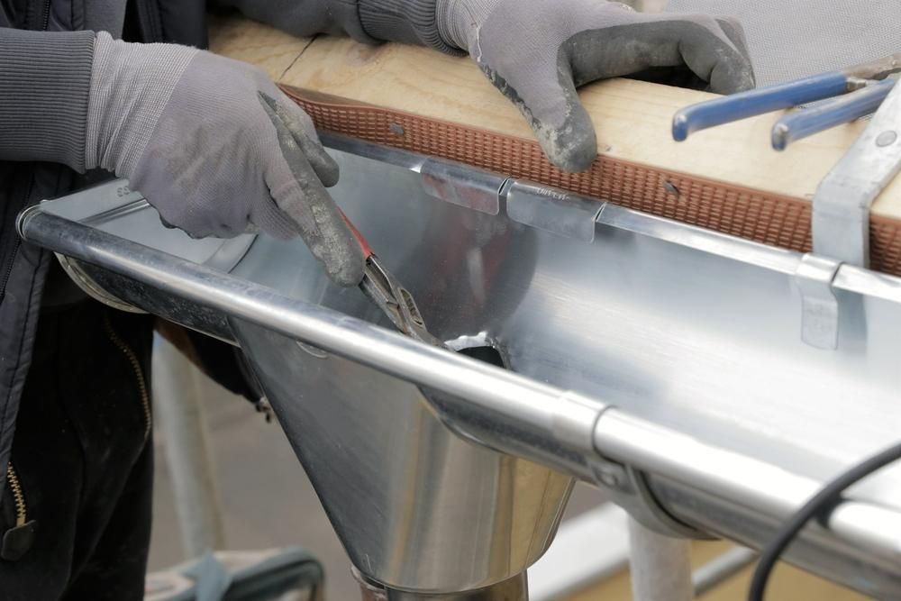 A Man Is Working on A Metal Gutter — Coffs Coast Plumbing in Korora, NSW