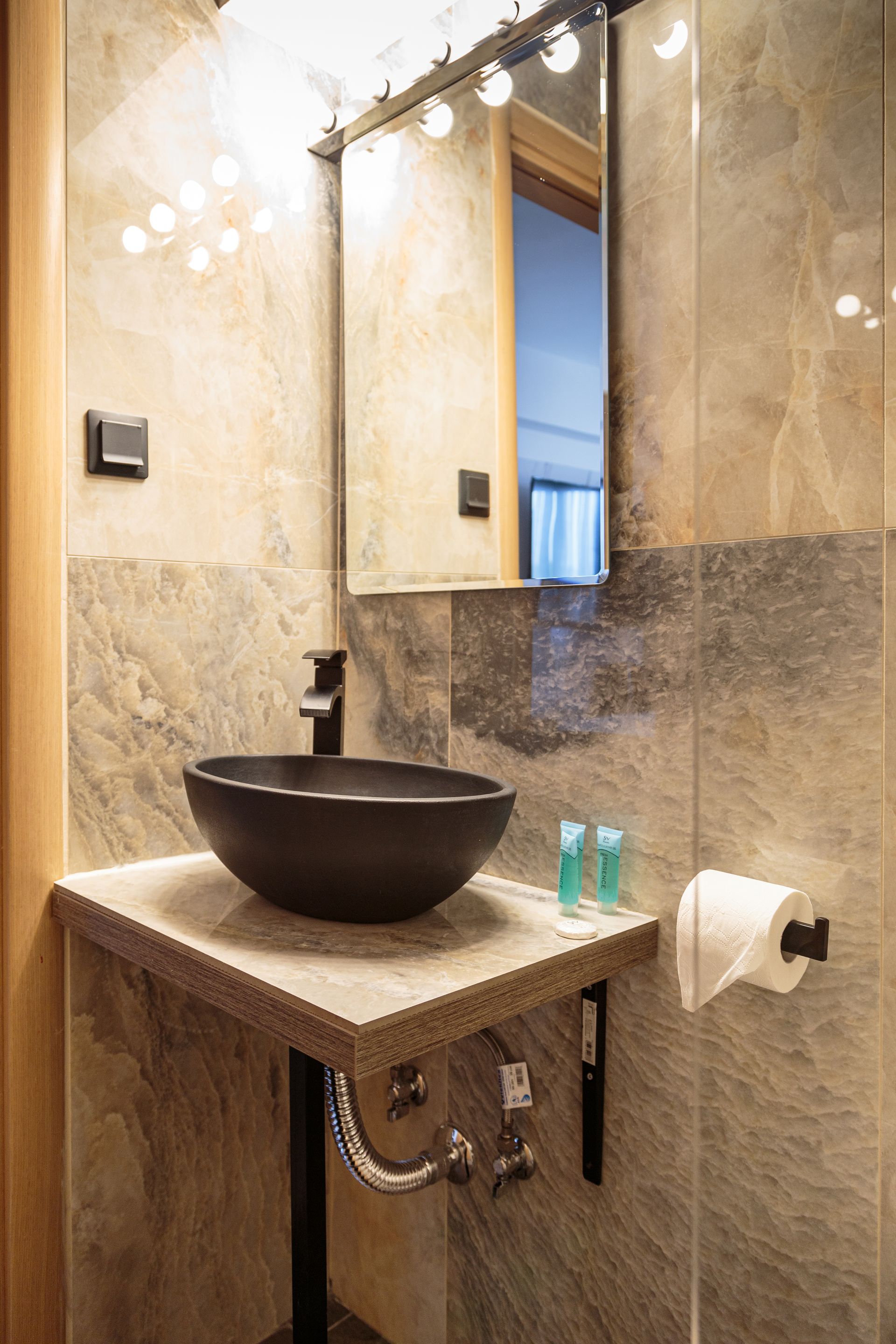 Small bathroom with glass shower, toilet, and dark vanity on gray tiled walls.