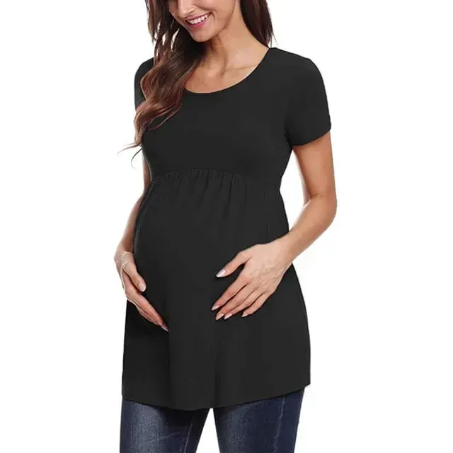 Mujer embarazada con túnica de maternidad negra y vaqueros, sujetándose la barriga.