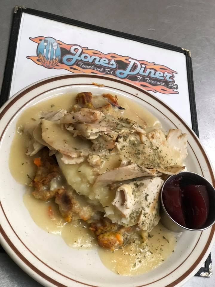 A plate of turkey, mashed potatoes, and stuffing covered in gravy at Jones Diner, served with a side of cranberry sauce.