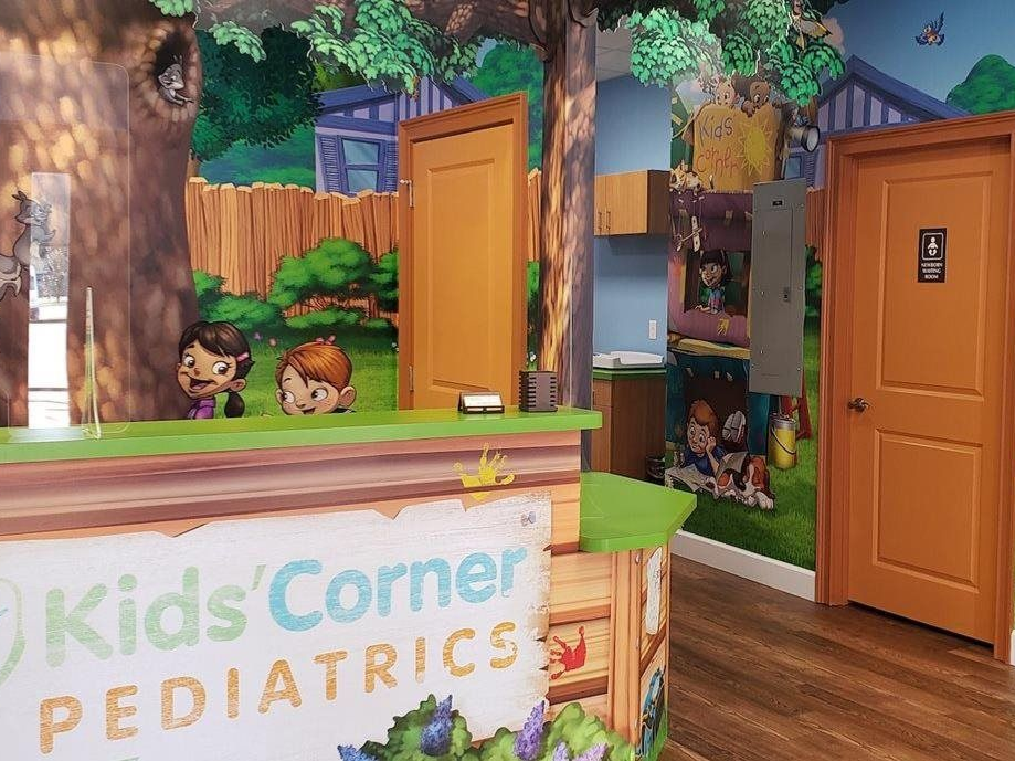 Kids Corner Pediatrics reception with colorful forest mural and open wooden door