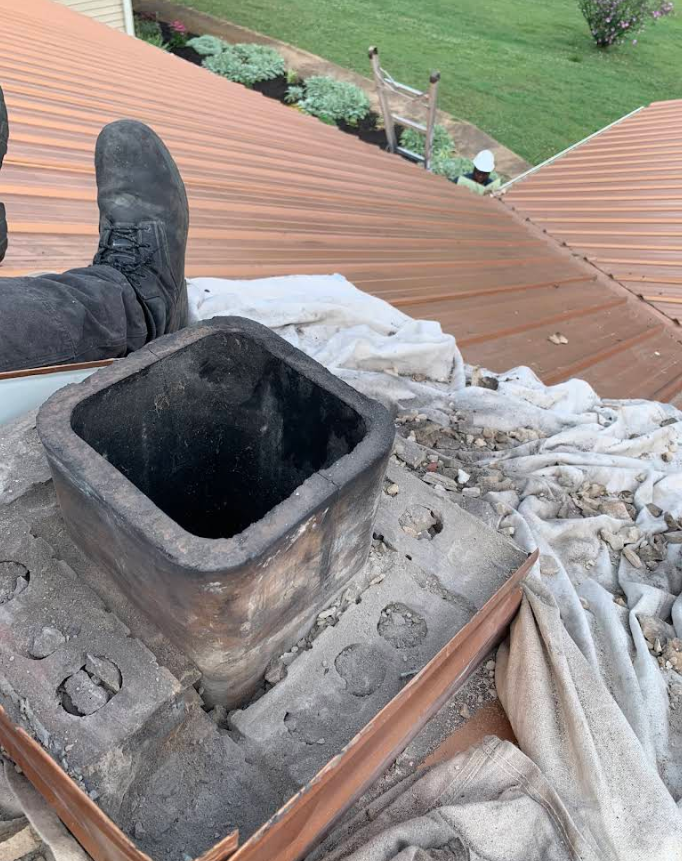 Roof repair scene with a square chimney opening, boots visible, and a tarp over debris on a sloped roof.