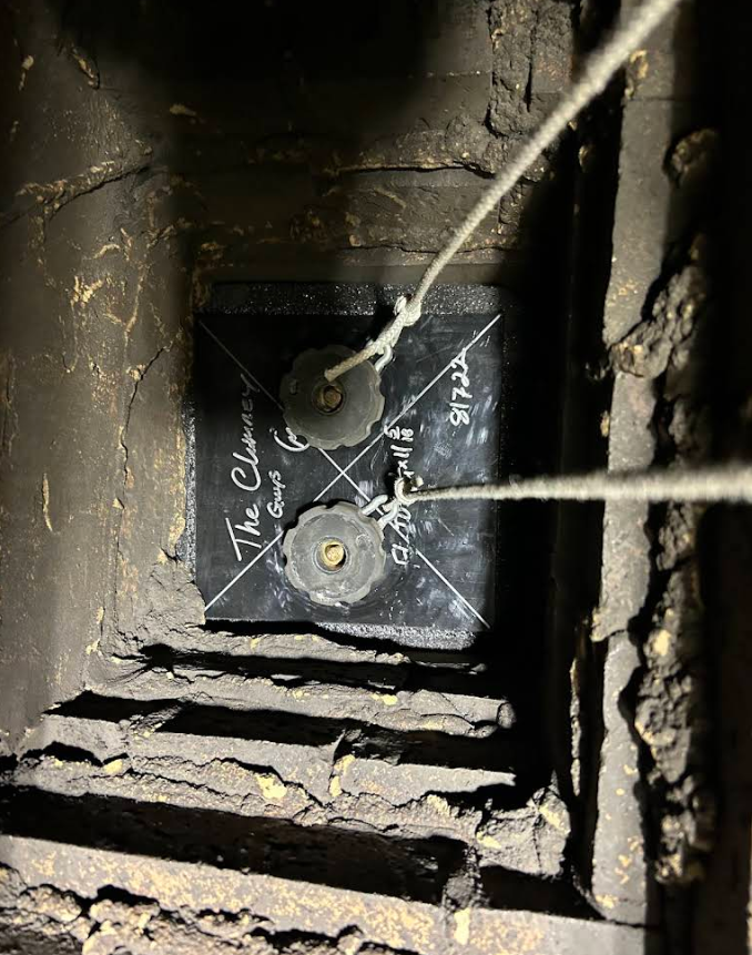 Dusty electrical box with two wires and chalk markings inside a wall opening