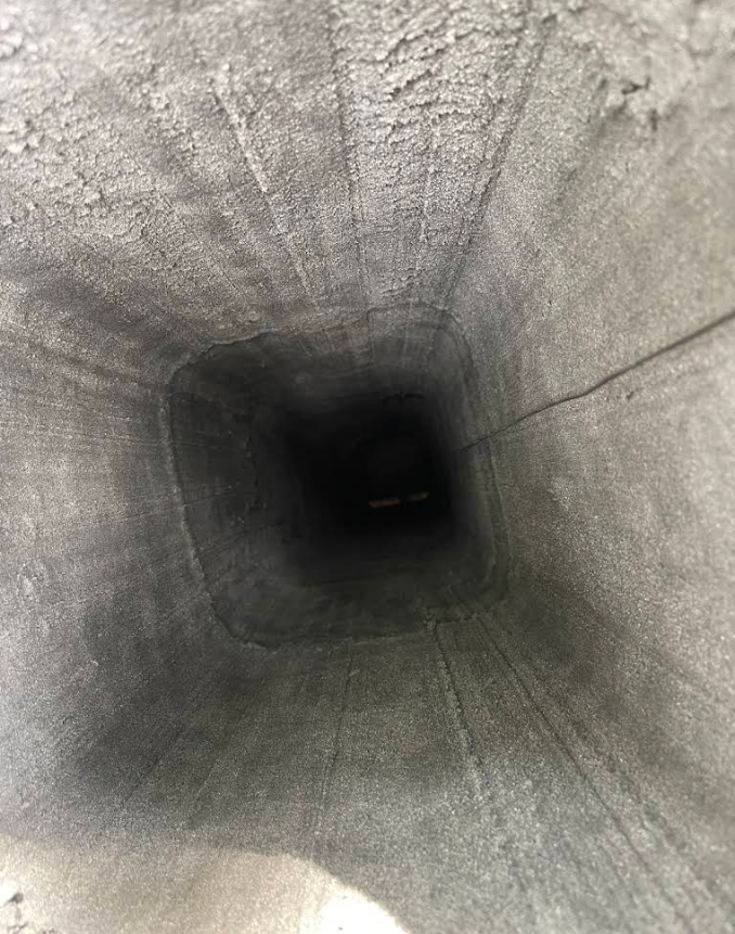 Inside of a square concrete tunnel, dark opening at the far end.