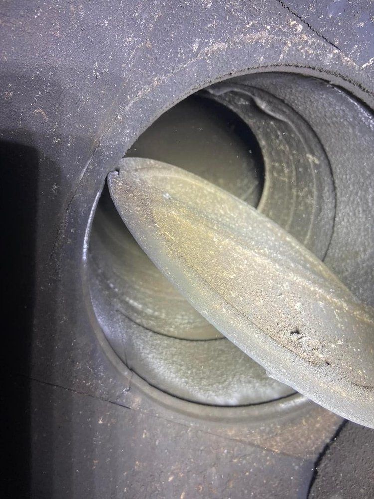 Close-up of a dusty gray plastic hose port with a translucent hose inserted.