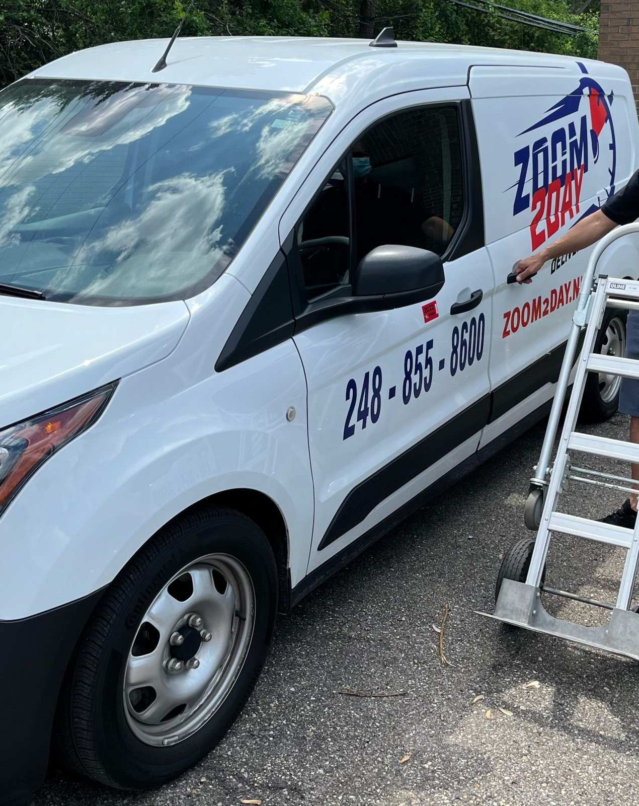 White Zoom Boat van with phone number, person opening door, parked outdoors.
