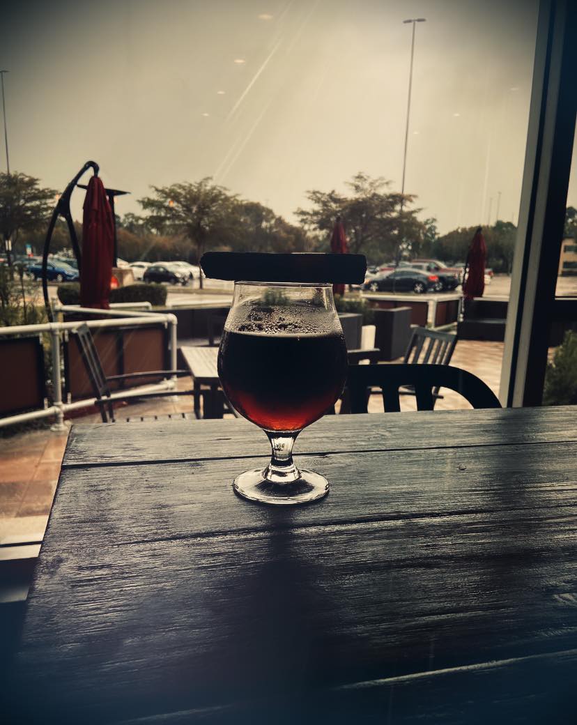 A glass of beer sits on a wooden table