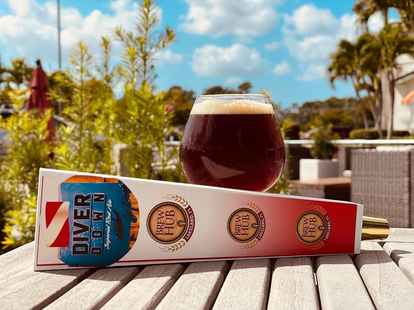A glass of beer is sitting on a wooden table next to a box that says diver down