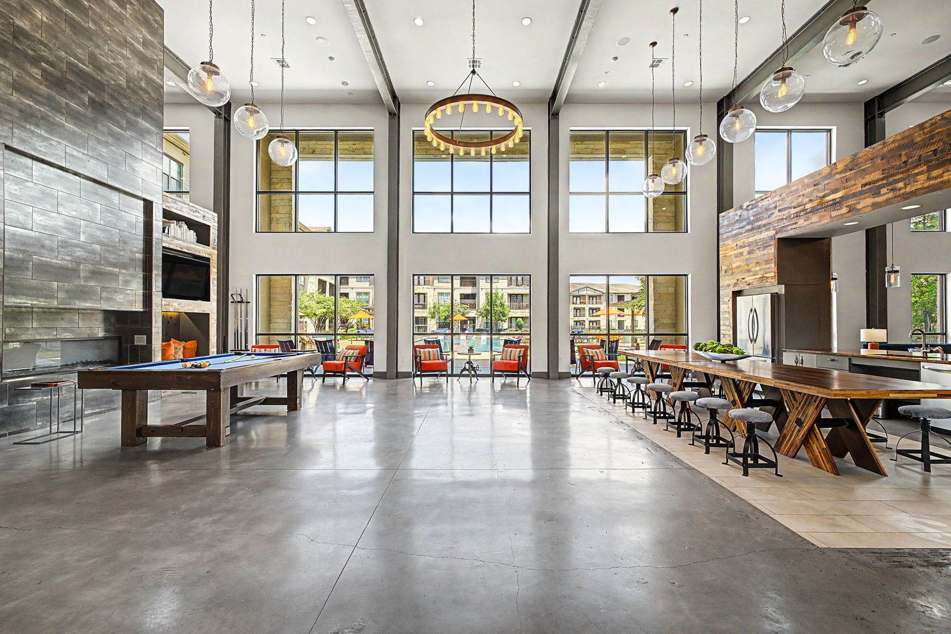 Spacious modern restaurant interior with high ceilings, large windows, stone walls, and wooden tables at Olympus Auburn Lakes in Spring, TX.