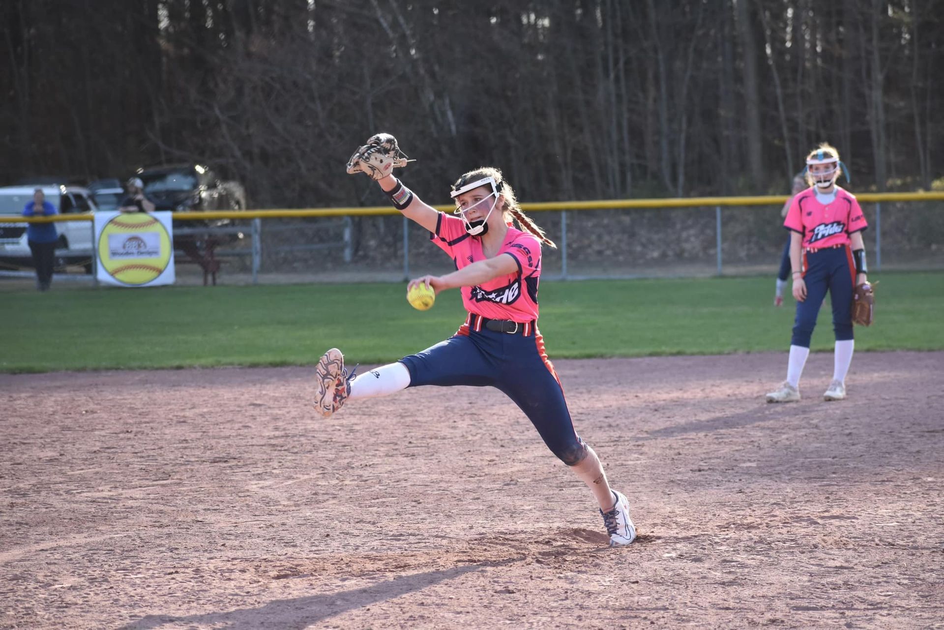 A girl is playing softball on a field and throwing a ball.