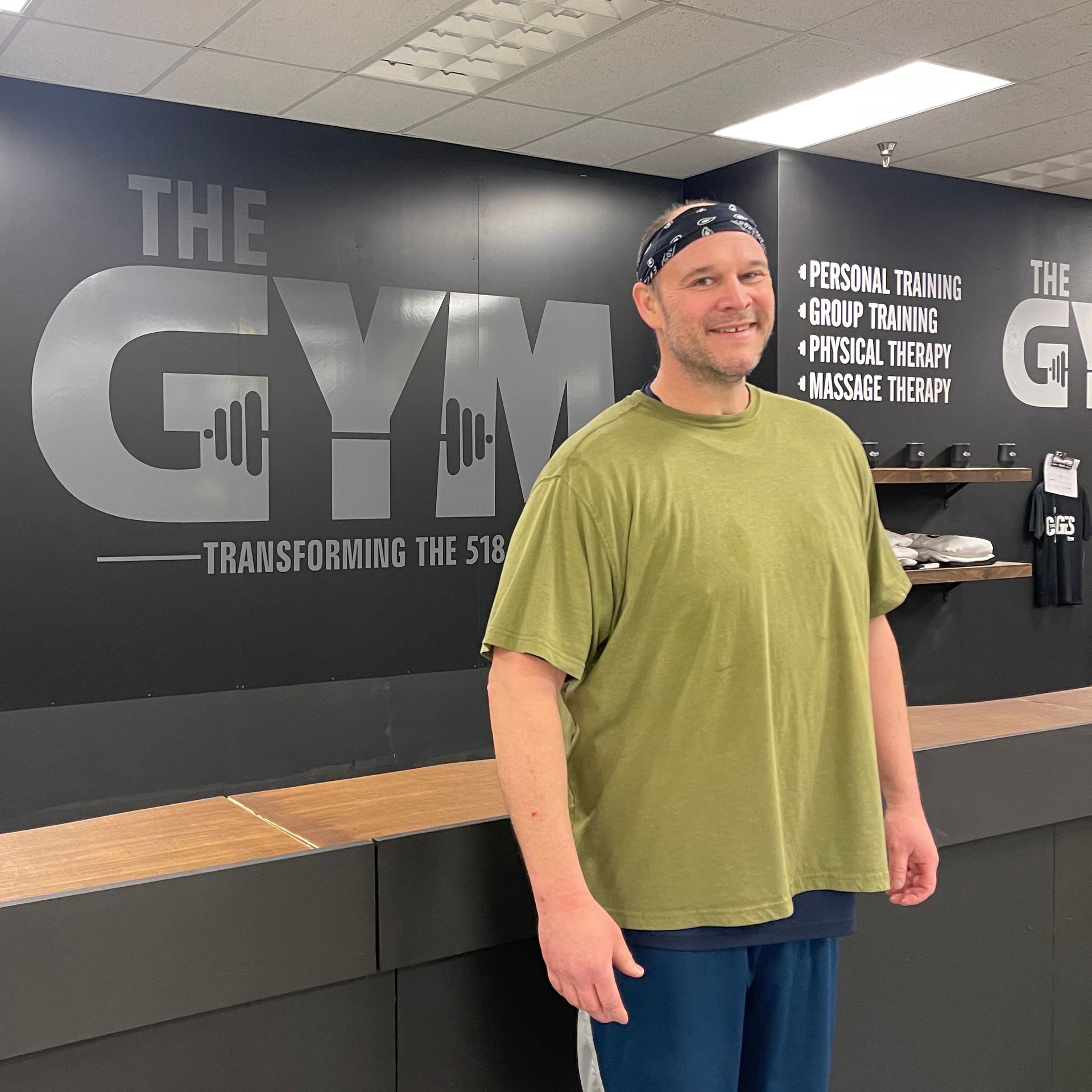 A man standing in front of a sign that says the gym