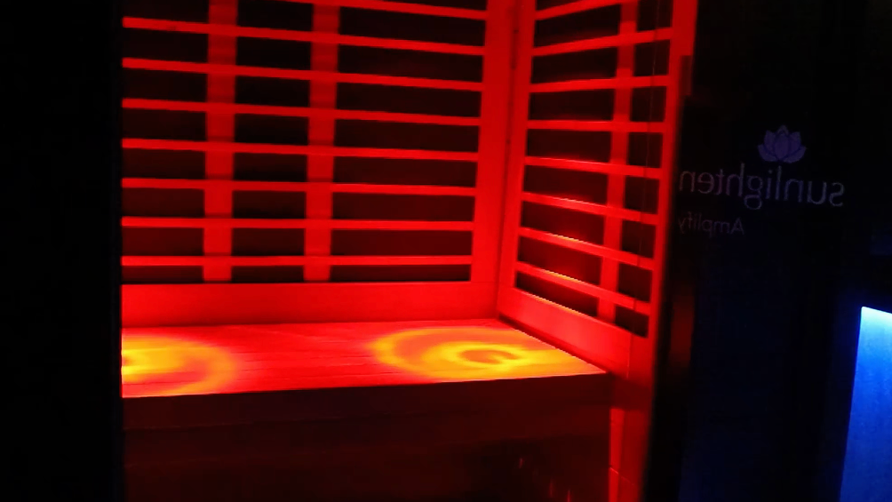 A red light is shining on a shelf in a dark room.