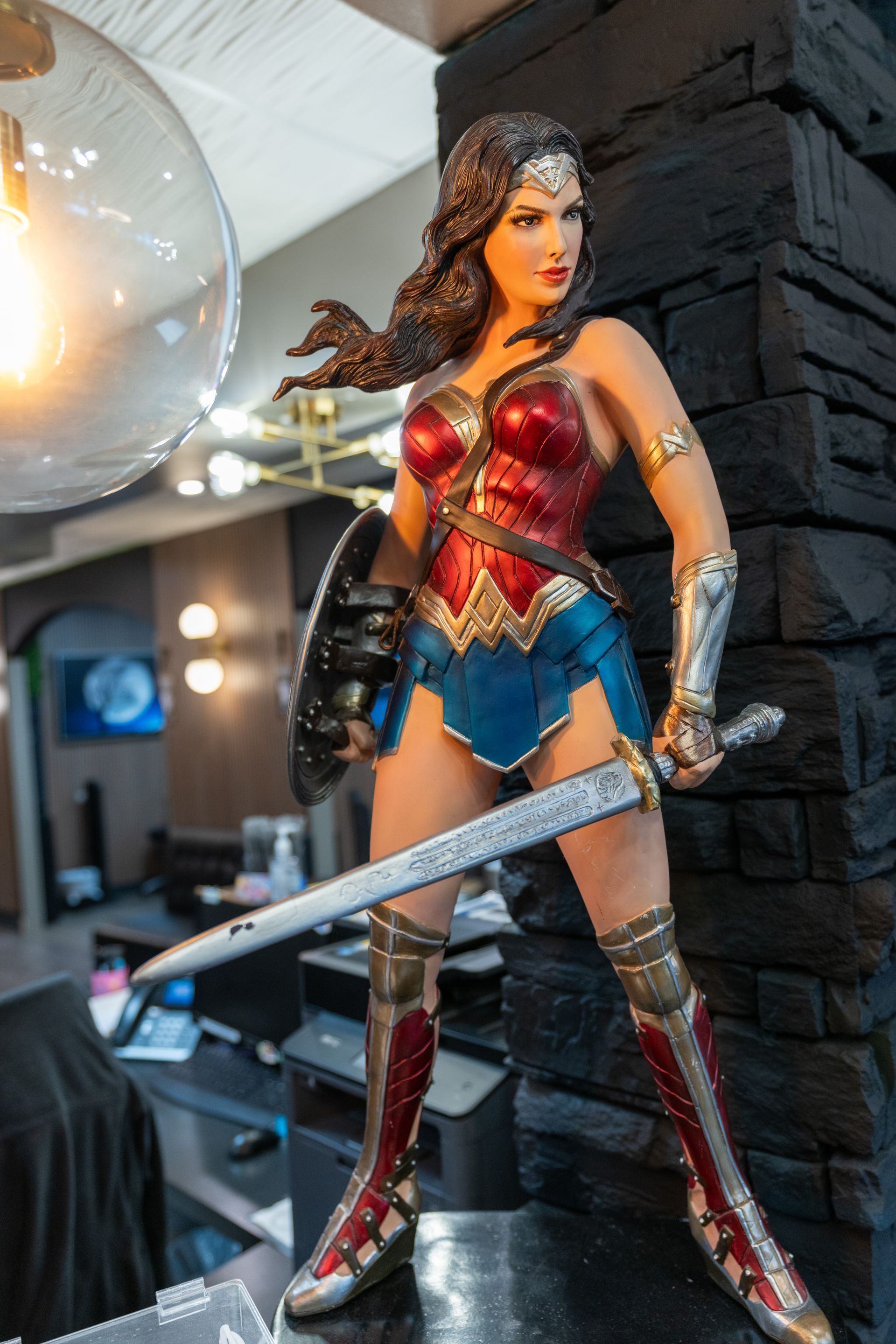 Wonder Woman figure in red, blue and gold armor holding a sword in an indoor display area