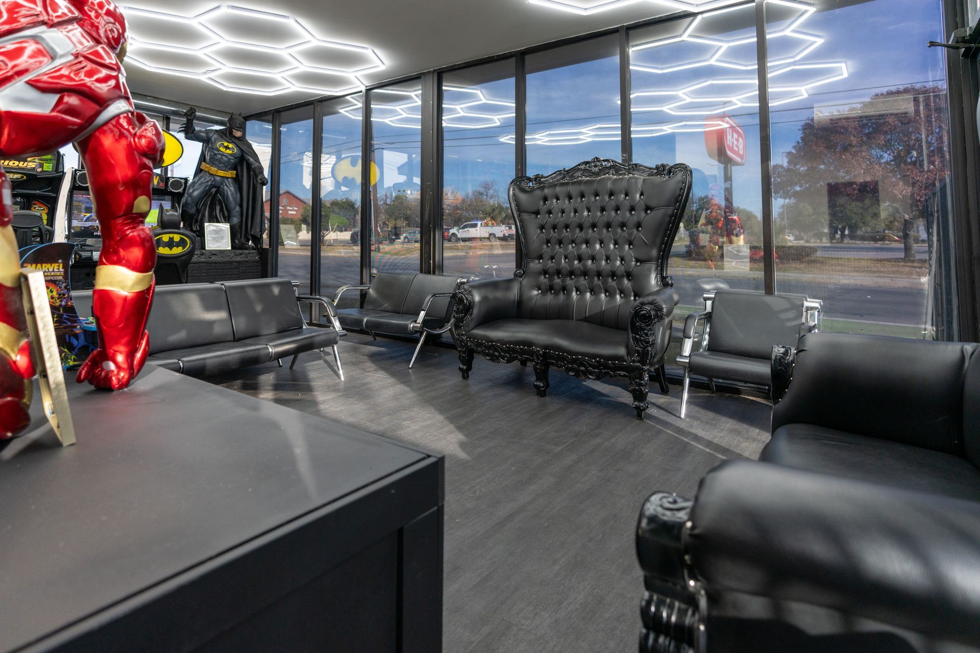 Modern office lounge with black leather chairs, a table, and large windows overlooking the street