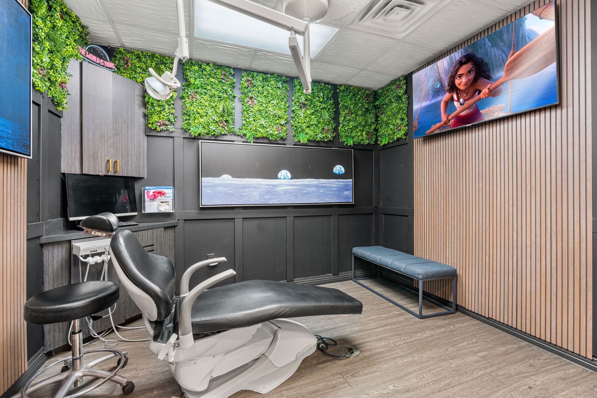 Modern dental exam room with chair, wall monitor, and wood-paneled accent wall