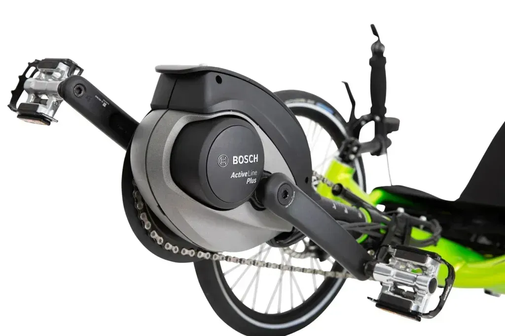 Close-up of a black electric bicycle mid-drive motor and rear wheel on a green frame