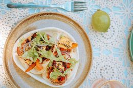 A plate of food with a fork and a lime on a table.