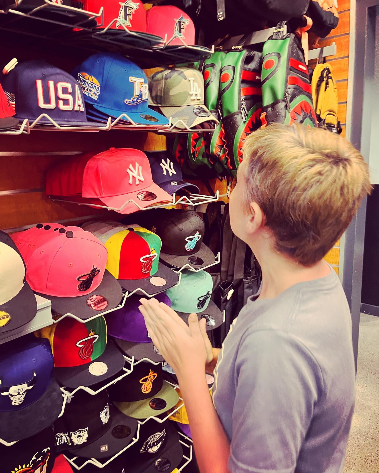 Person browsing a wall of colorful baseball caps in a store