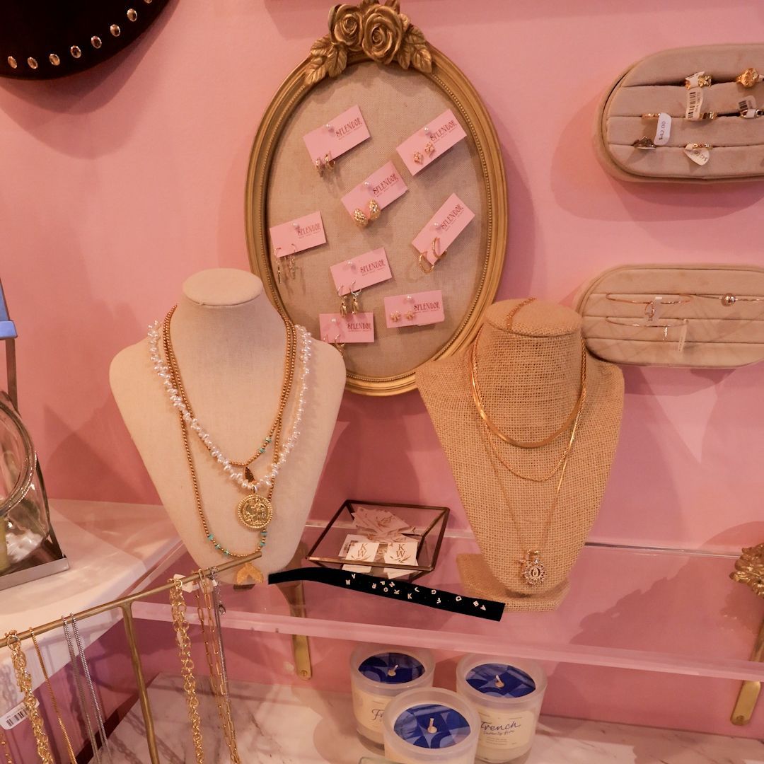 Gold necklaces and earrings displayed on a pink wall at Splendor, a gift shop at Redstone in Park City.