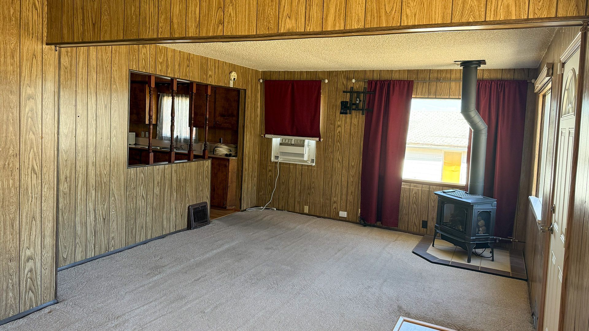 Cozy front living room featuring wood-paneled walls and a freestanding wood-burning stove