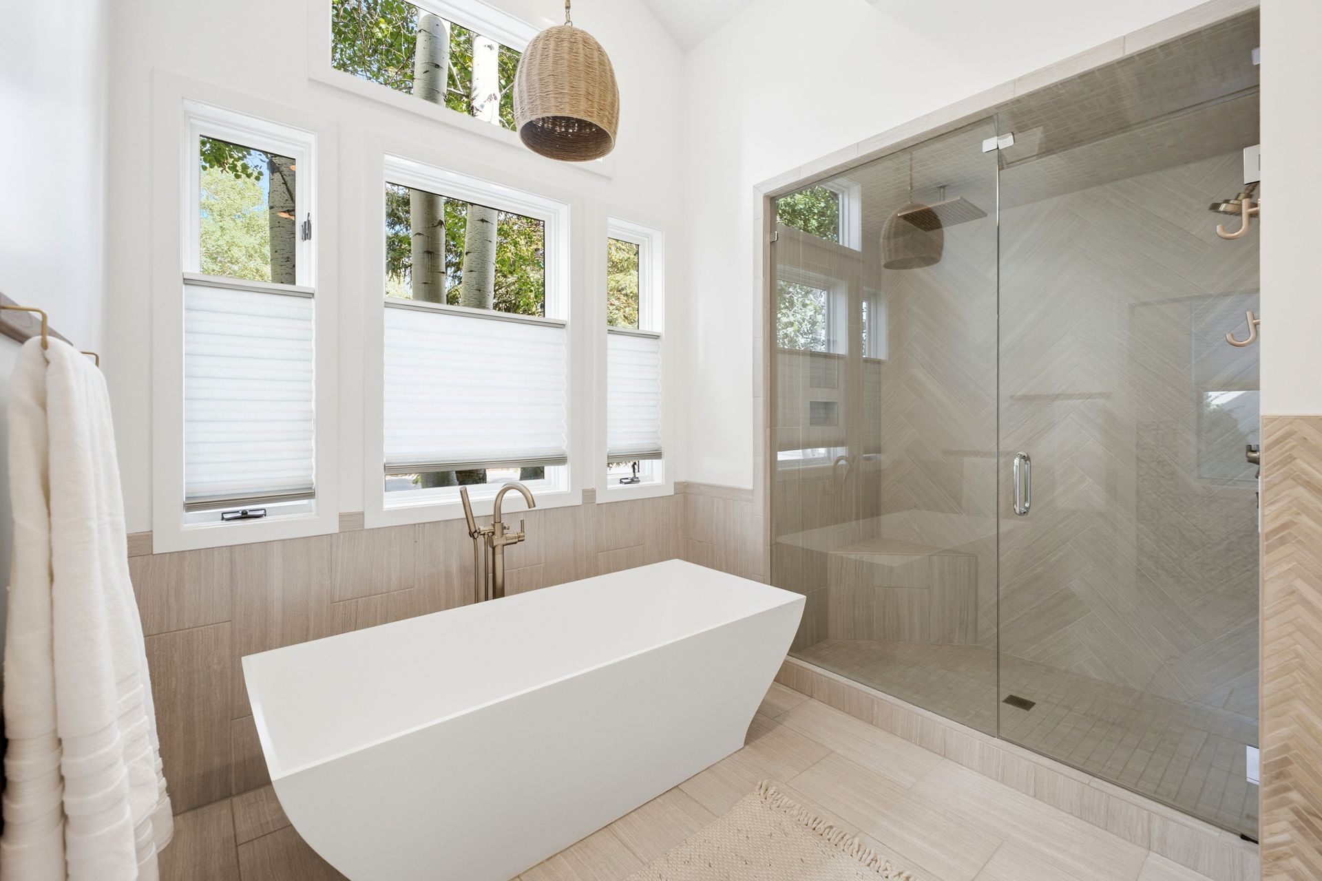 Remodeled spa-inspired primary bathroom featuring a modern freestanding soaking tub, radiant tile floors, and a large glass-enclosed steam shower.
