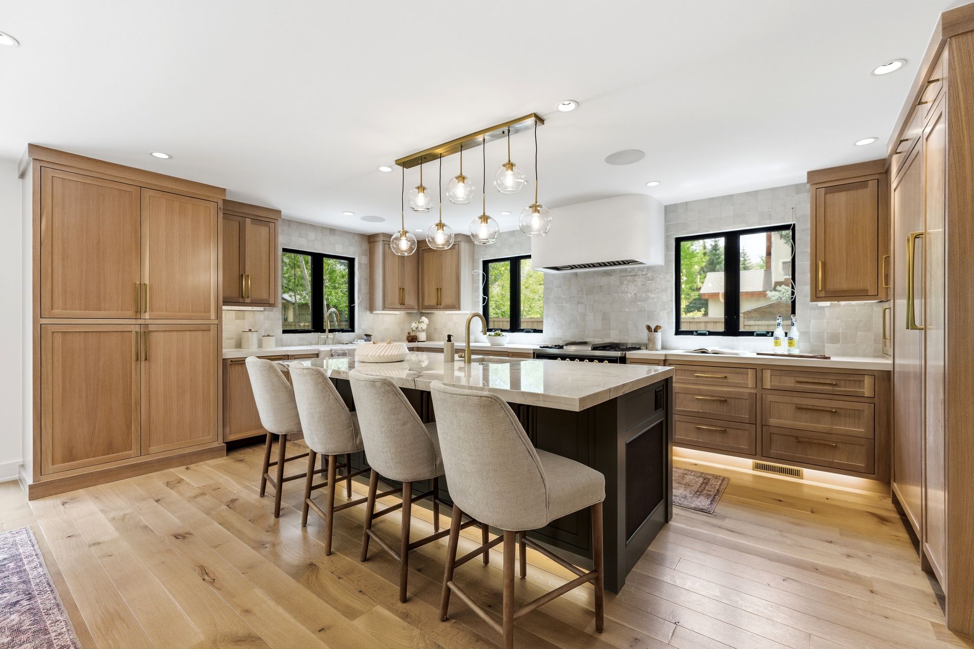 Bright modern kitchen with large island, wood cabinets, bar stools, and pendant lights