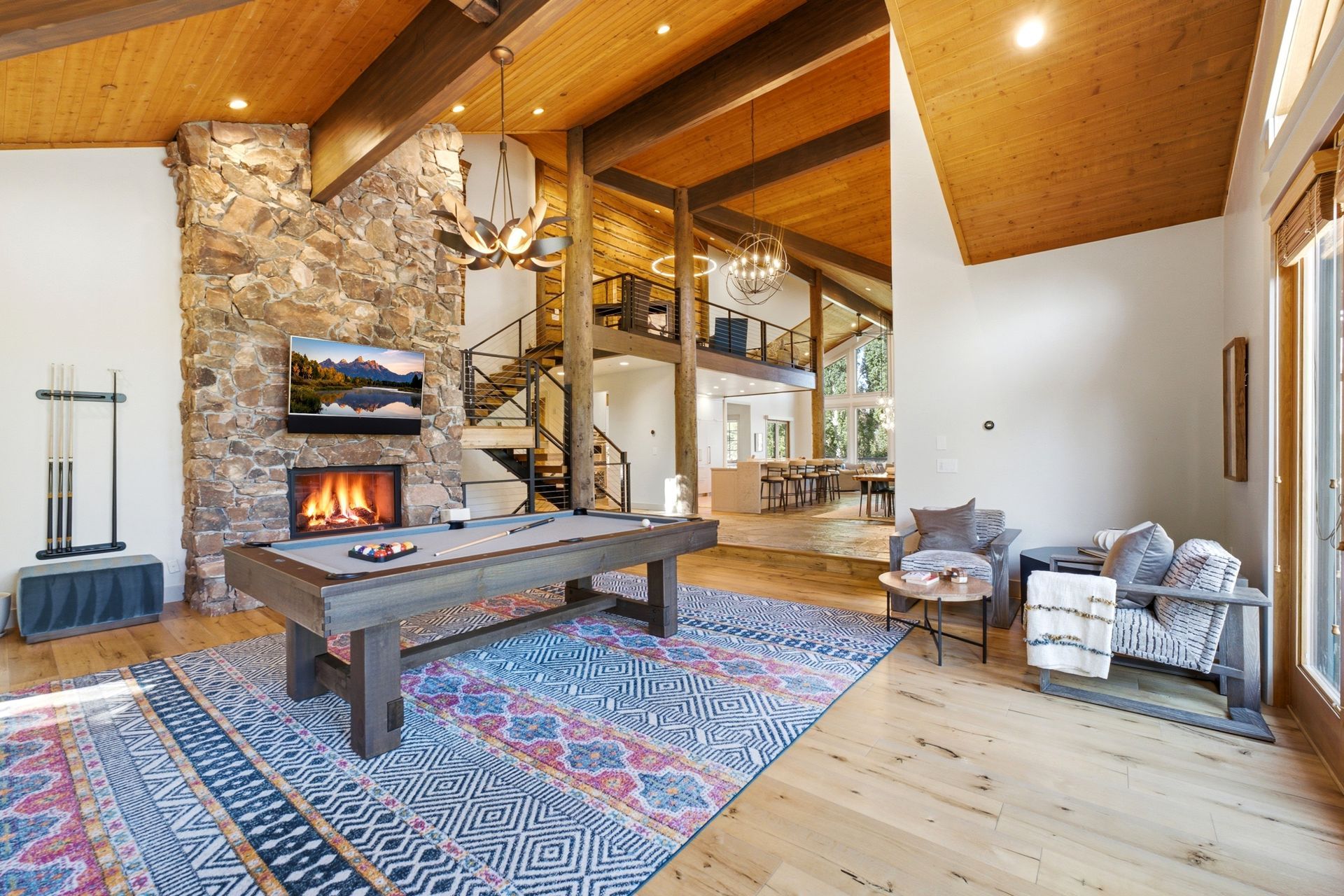 Great room at 2490 Silver Cloud Dr with stone fireplace, pool table, and open staircase to the loft