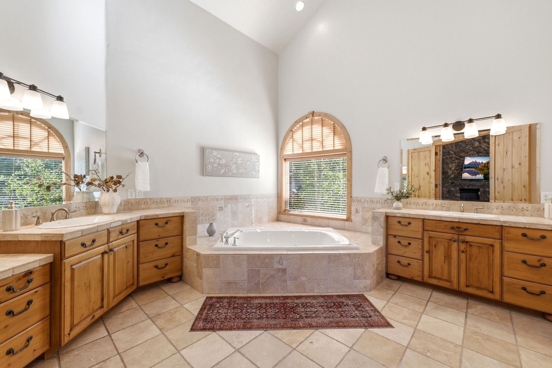 Spa-inspired primary bathroom with dual natural stone vanities and a deep jetted soaking tub.
