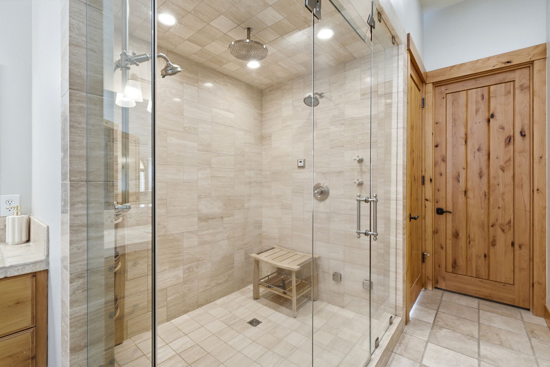 Walk-in steam shower with glass enclosure and custom stone tile work.