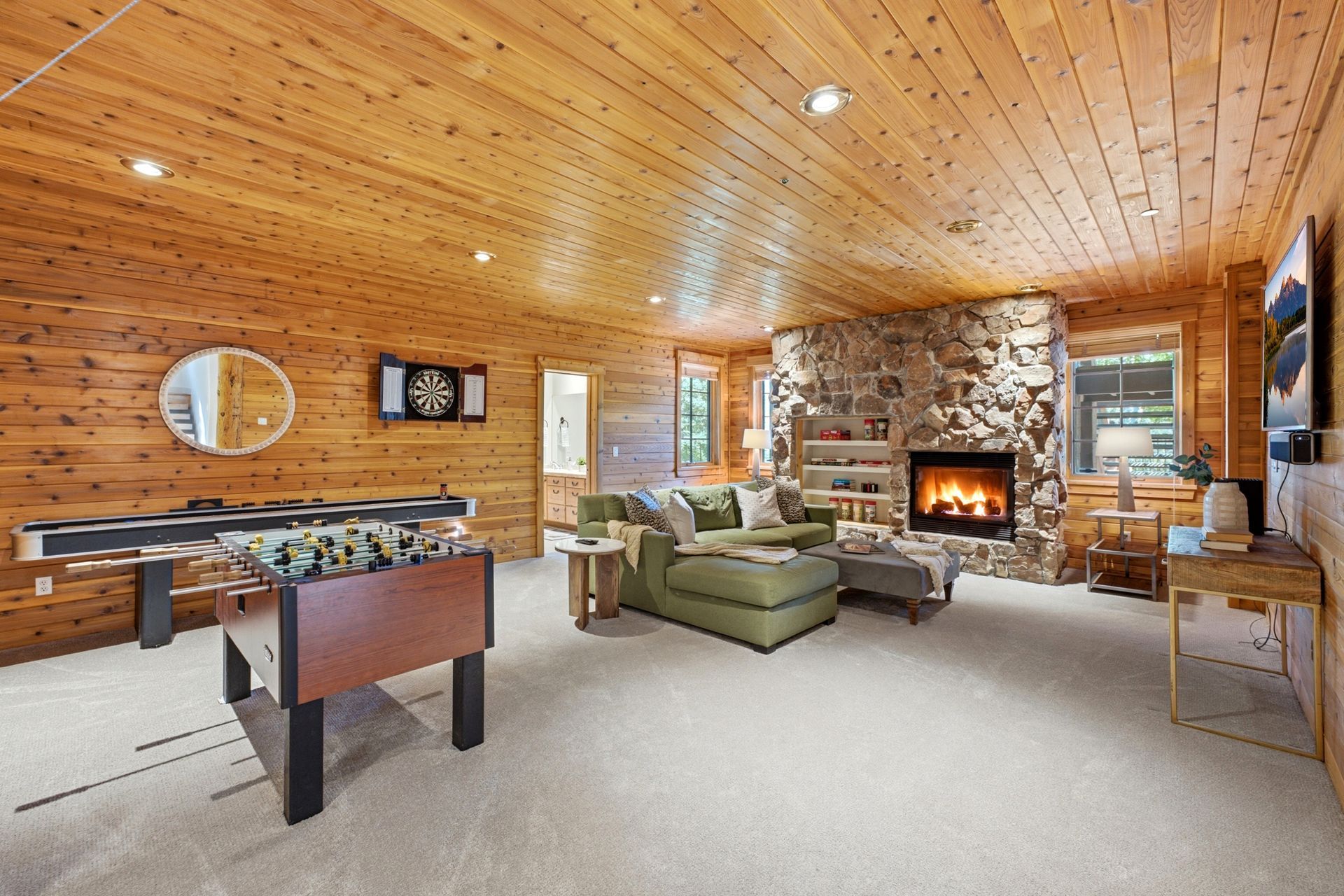Lower level family room at 2490 Silver Cloud Dr with knotty pine walls, stone fireplace, foosball and shuffleboard