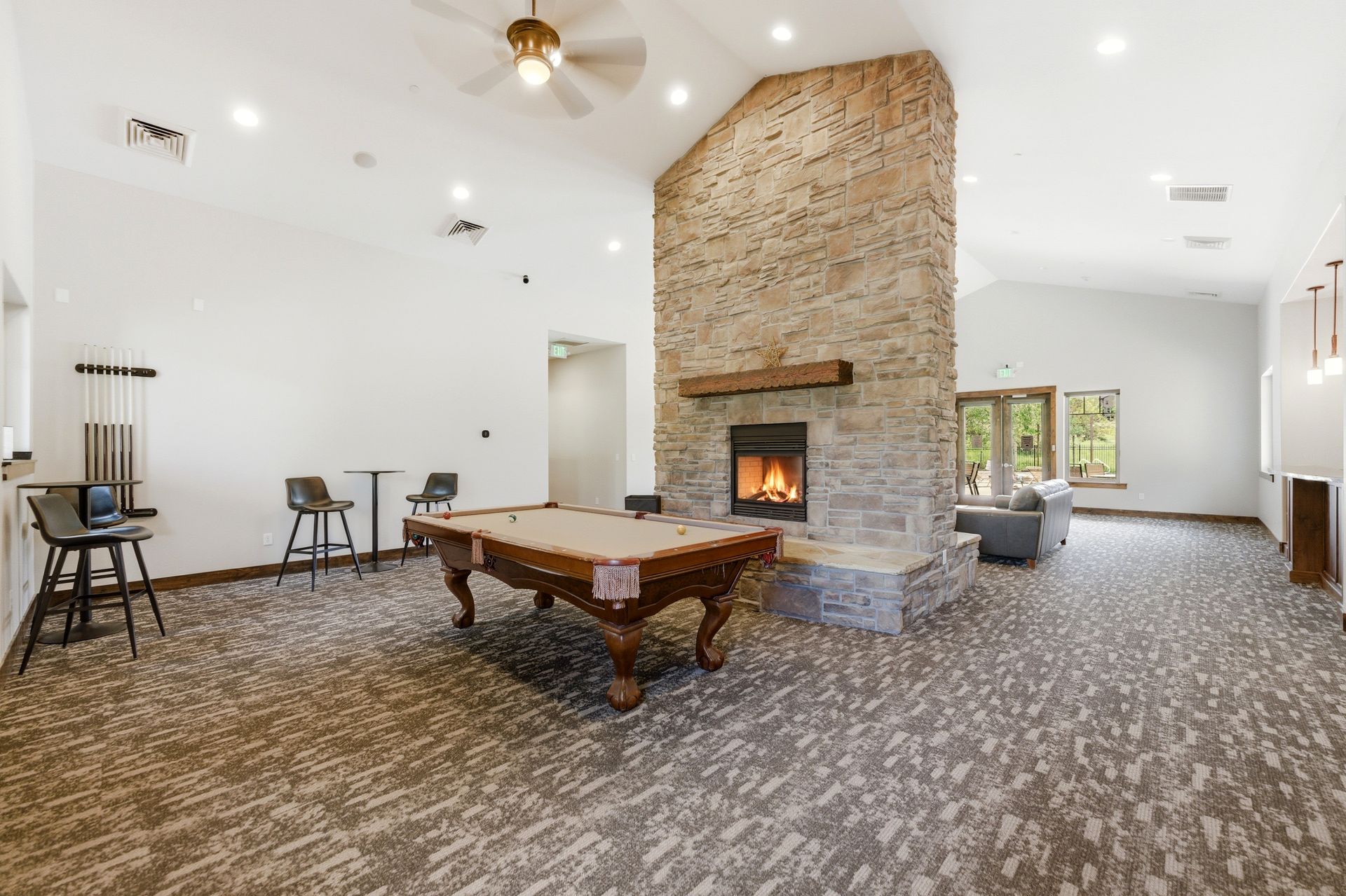 Park's Edge community clubhouse interior featuring a pool table, stone fireplace, and comfortable seating areas for residents.