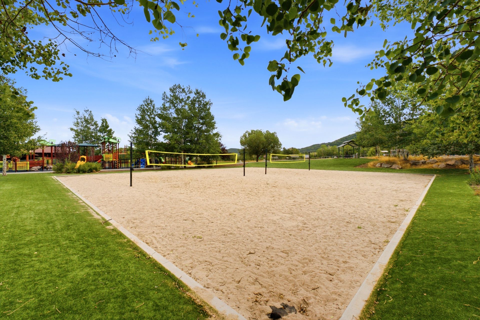 Outdoor sand volleyball court in a green park with trees and blue sky