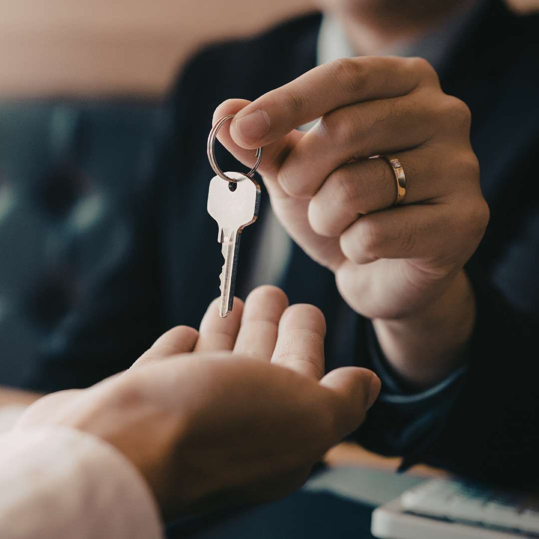 A real estate agent handing over new house keys to a buyer, representing the final settlement deadline and a successful property closing.