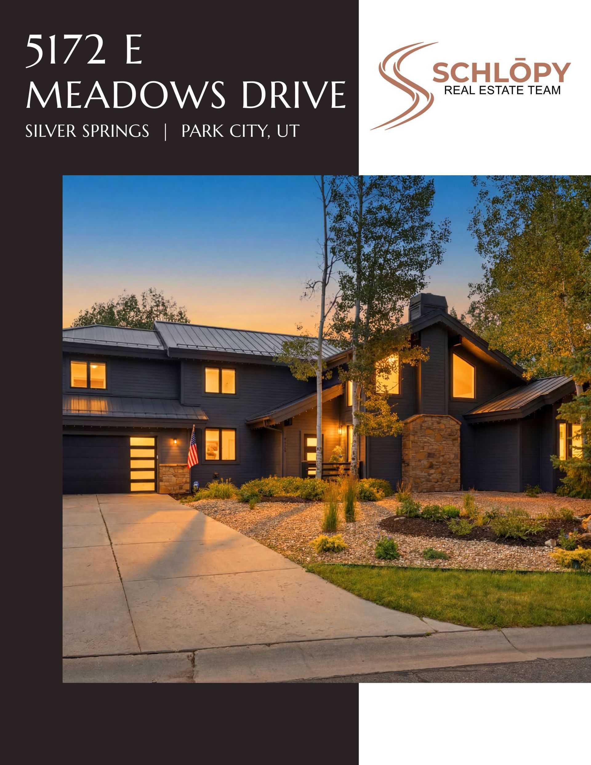 Modern dark-stone house at dusk with lit windows, driveway, and tall trees; real estate listing for 5172 E Meadows Drive