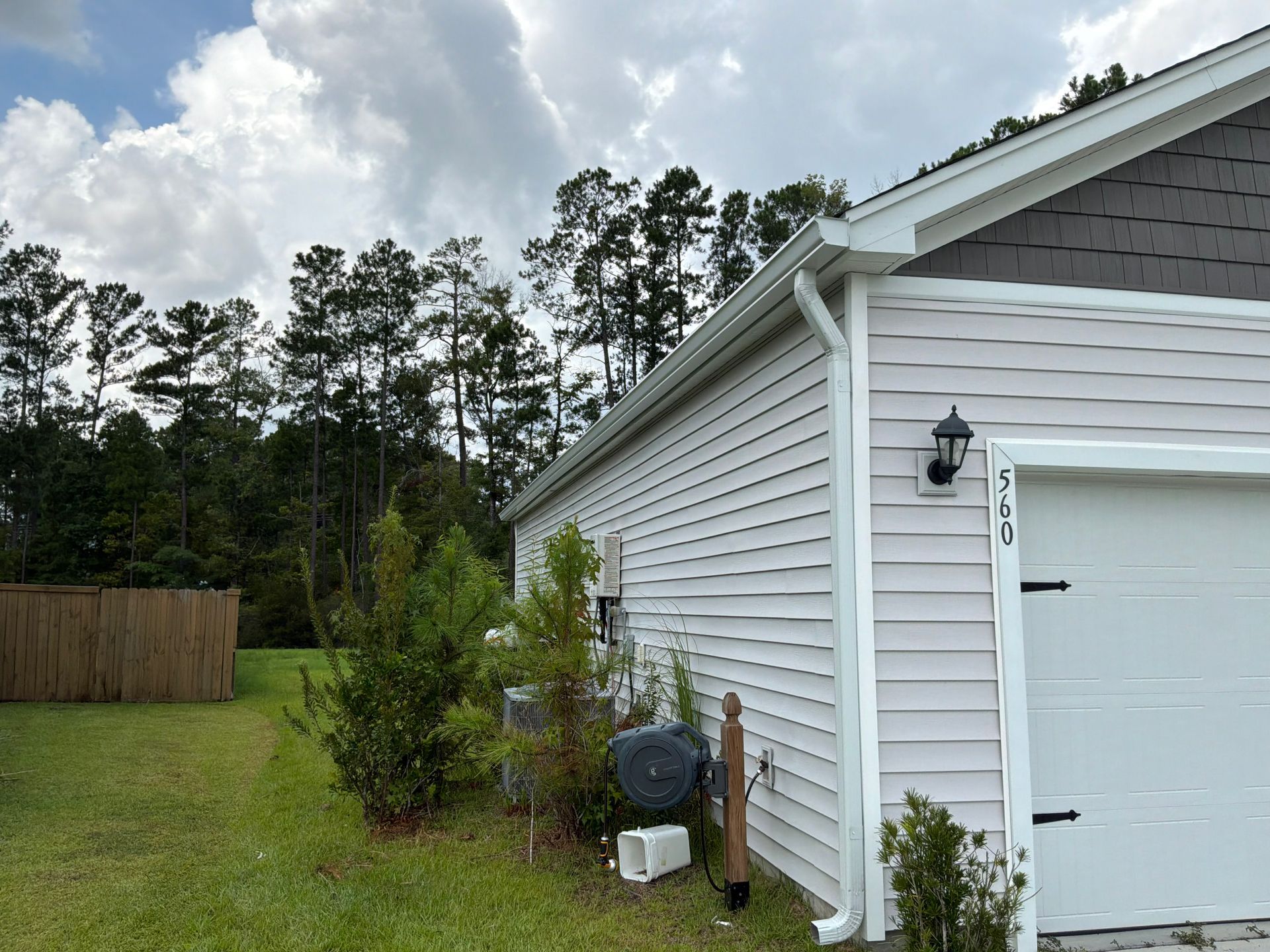 A West Ashley homeowner at a kitchen table comparing two roofing estimates while a Charleston Roofs and Windows inspection manager shows tablet photos of rotted decking under an old shingle layer on a 1950s Byrnes Downs cottage. The image represents honest roofing estimates in West Ashley SC, where the roofer checks the attic and the roof, explains repair versus replacement, confirms City of Charleston or Charleston County permits and assigns a named W2 project manager.